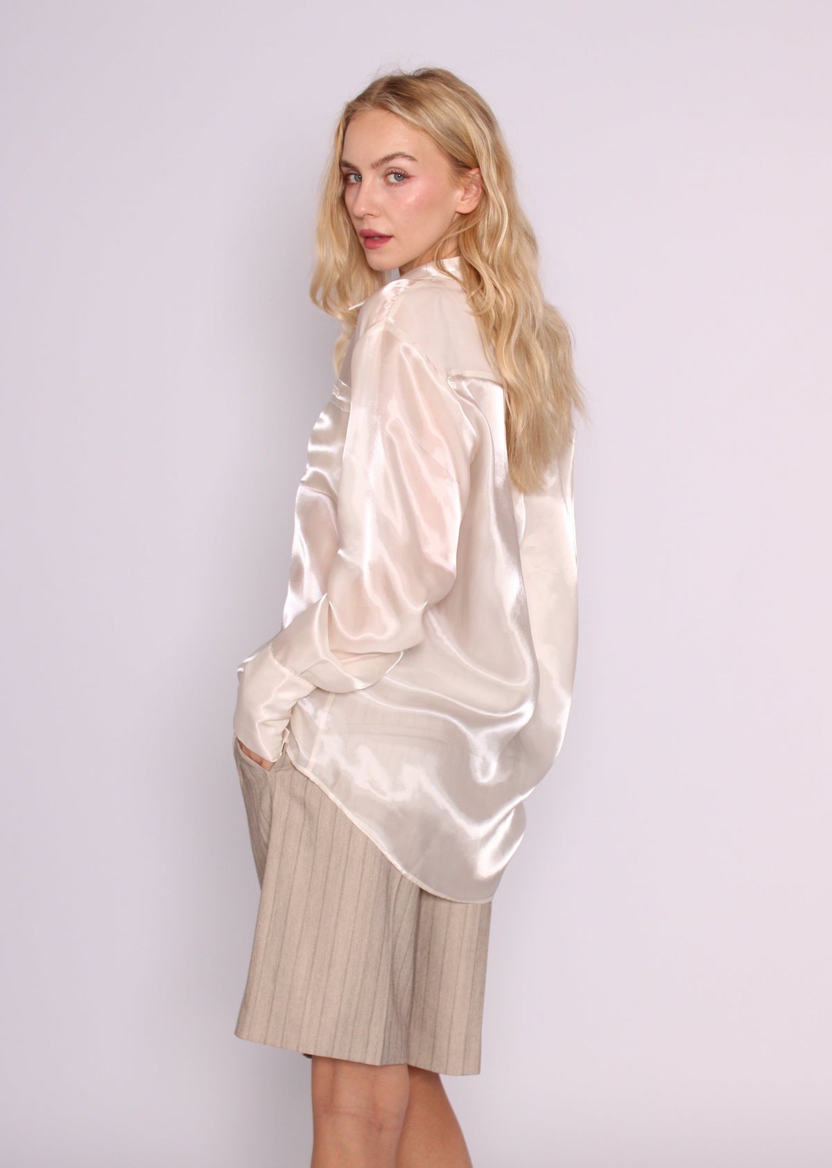 Three-quarter back view of the ivory BRISTOWE Mirage Shirt, showing its loose fit and curved hem, worn with Ryden shorts