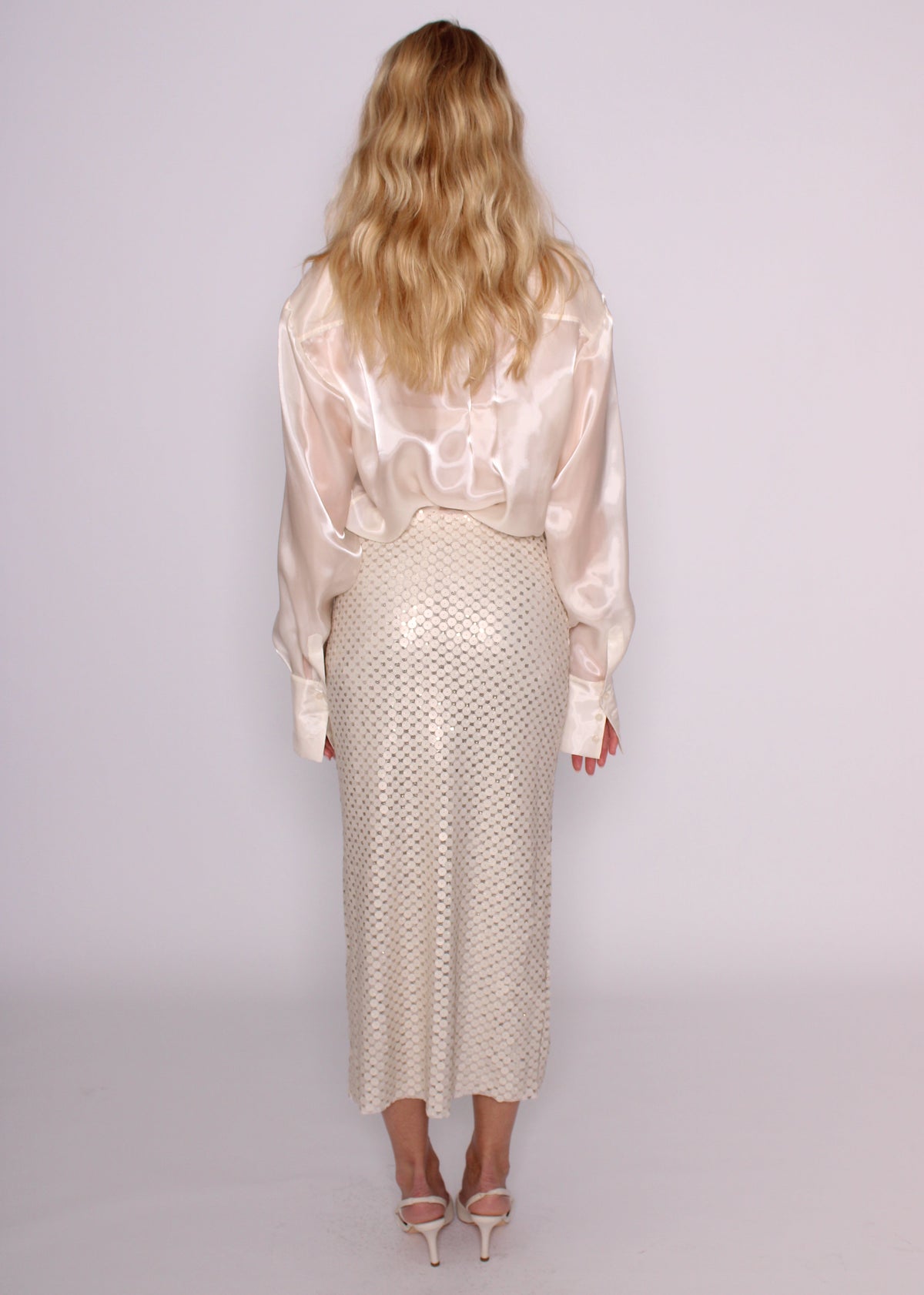 Back view of the BRISTOWE Corine ivory sequin maxi skirt showing its shimmering texture, styled with an ivory shirt.