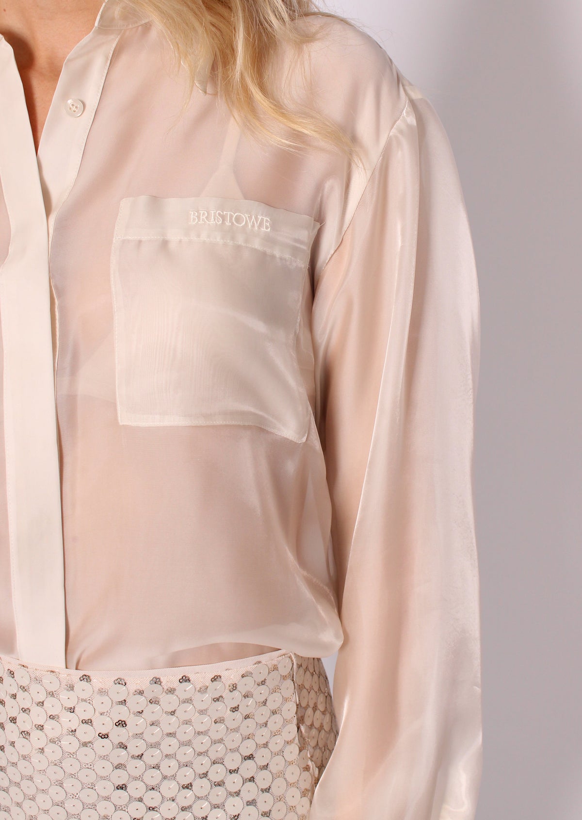 Close-up of the BRISTOWE Mirage Shirt’s sheer ivory fabric, button front and chest pocket with embroidered BRISTOWE logo